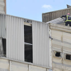 Un bombero levanta uno de los paneles del techo de la nave tras la deflagración. / REPORTAJE GRÁFICO: VALENTÍN GUISANDE-