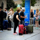 Varios turistas esperan el autobús al aeropuerto en la plaza de Catalunya.-FERRAN NADEU