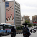 Conductores iranís circulan junto a un edificio en el que aparece una pintada contra Estados Unidos en Teherán.-EFE / ADEDIN TAHERKENAREH