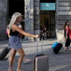 Turistas con sus equipajes pasan por delante de la tienda Tiffany en el paseo de Gràcia.-FERRAN NADEU