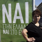 Una mujer espera el autobús junto a un cartel que pide el voto positivo en el referéndum, en el que se lee: "Sí a Grecia, sí al euro".-Foto:   EFE / YANNIS KOLESIDIS