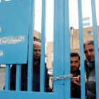 Un grupo de palestinos detrás de la valla de la oficina de la agencia de la ONU para los refugiados palestinos (UNRWA) durante una protesta en la ciudad de Cisjordania.-EFE / ABED AL HASHLAMOUN