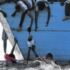 Unos inmigrantes tratan de sacar a un niño del mar frente a las costas de Libia, en una foto de archivo.-ARIS MESSINIS