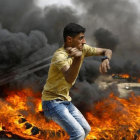 Un palestino se dispone a lanzar piedras entre los neumáticos incendiados contra las tropas israelís, en las protestas junto a la frontera de la Franja de Gaza, el 20 de abril.-MOHAMMED ABED