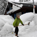 Una mujer limpia la nieve de los accesos a su casa en Val dIsere, en los Alpes franceses.-AFP / JEAN-PIERRE CLATOT