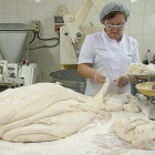 Encarna Terrón corta porciones de masa, que pesa en una balanza tradicional, en la panadería de Carbajales de Alba (Zamora).-MIRIAM DENEIVA