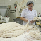 Encarna Terrón corta porciones de masa, que pesa en una balanza tradicional, en la panadería de Carbajales de Alba (Zamora).-MIRIAM DENEIVA