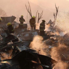 Un grupo de bomberos trabaja entre los escombros de varias casas devoradas por las llamas en Valparaiso.-REUTERS / RODRIGO GARRIDO