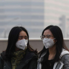 Dos chicas se protegen de la contaminación en Pekín el pasado lunes.-AFP / GREG BAKER