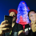 Dos personas utilizando su teléfono móvil frente a la Torre Agbar-EL PERIÓDICO