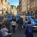 Vecinos y turistas circulan por el centro de Münster, entre furgonetas de la policía, tras el atropello de ayer.-/ AFP