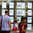 Un hombre y dos niñas observan las ofertas de viviendas en una agencia inmobiliaria del paseo de Maragall de Barcelona.-ARCHIVO / FERRAN NADEU