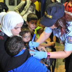 Una agente de policía checa escribe el número en la mano de un niño.-AP/IGOR ZEHL