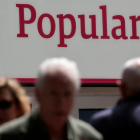 Personas pasando por delante de unas oficinas del Banco Popular-REUTERS