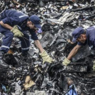 Dos agentes buscan entre los restos del vuelo MH17 de Malaysia Airlines, el pasado 20 de julio en Donetsk (Ucrania).-AFP