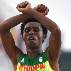 El atleta etíope Feyisa Lilesa cruzando la línea de meta tras acabar segundo en el maratón de Río.-OLIVIER MORÍN / AFP