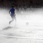 Un joven, dentro de la fuente del Rincón de Bécquer, se refresca gracias al agua que expulsa los surtidores. / A. M.-