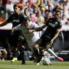 Cristiano Ronaldo cae el suelo entre dos defensas del Granada.-AGUSTÍN CATALÁN