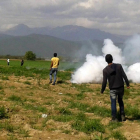 La guardia fronteriza macedonia lanza gases lacrimógenos contra los refugiados que intentaban cruzar la frontera desde Idomeni, este domingo.-EFE