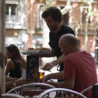 Un camarero atiende a unos clientes.-PAULA GONZÁLEZ