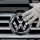 Un empleado coloca el logotipo de Volkswagen a un vehículo.-AFP / RALF HIRSCHBERGER