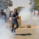 Manifestantes se protegen de los gases lacrimógenos de las fuerzas de seguridad en Jartum.-EFE