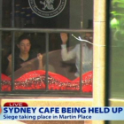 Dos de los rehenes, contra las ventanas del café Lindt Chocolate Cafe, del centro de Sídney, este lunes.-Foto: AP