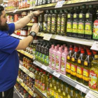 Un trabajador ordenando las botellas de aceite en un supermercado.-JOAN CORTADELLAS