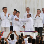 Santos y Timochenko se dan la mano entre los aplausos de Ki-mon, Castro y el rey emérito Juan Carlos, entre otras personalidades.-AFP / LUIS ACOSTA