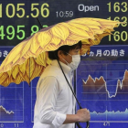 Un hombre pasa ante un sociedad de bolsa en Tokio en cuyo paneles informativos se muestra la caída del mercado.-Koji Sasahara