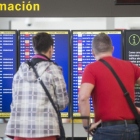 Dos viajeros observan el panel de salidas en el aeropuerto de El Prat, en plena huelga de controladores en Francia.-EFE