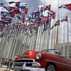 Un coche clásico americano pasa al lado de la embajada estadounidense en La Habana, donde ondean decenas de banderas de Cuba.-AP / DESMOND BOYLAN
