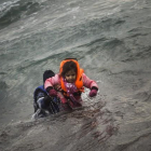 Un hombre ayuda a un niño cuyo barco ha naufragado este domingo en el Egeo.-AFP / Santi Palacios / AP