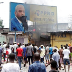 Opositores del presidente Kabila gritan consignas contra el mandatario mientras destruyen un cartel con su imagen, en Kinshasa, capital de la República Democrática del Congo, este lunes.-REUTERS / KENNY KATOMBE