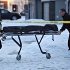 Dos agentes se llevan uno de los cadáveres encontrados en una casa de Edmonton, este martes.-Foto:   AP / JASON FRANSON