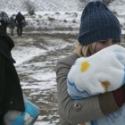 Una mujer migrante protege a su hijo con una manta mientras camina cerca de Miratovac (Serbia), este lunes.-AP / VISAR KRYEZIU