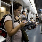 Una usuaria utiliza su móvil en el vagón de metro de la línea 3.-FERRAN NADEU