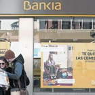 Unos turistas en Sevilla, ante una sede de Bankia.-REUTERS / MARCELO DEL POZO