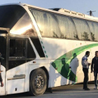 Varias personas permanecen junto a un autobús a la espera de la llegada del resto de evacuados civiles y combatientes.-EFE / MOHAMED BADRA