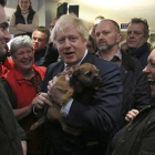 El primer ministro británico, Boris Johnson, sostiene un perro durante un encuentro con Paul Howell, el recién elegido diputado del Partido Conservador en Sedgefield, en el noreste de Inglaterra.-LINDSEY PARNABY (AP)