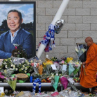 Un monje budista deja unas flores junto a la fotografía del empresario, a las afueras del estadio del Leicester.-AFP