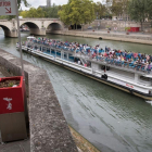 Un hombre utiliza un uritrottoir ante el paso de un bateau mouche en el Sena.-EL PERIÓDICO