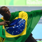 El Bolt camaleónico, envuelto en la bandera de Brasil.-AFP / ERIC FEFERBERG