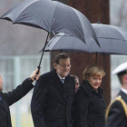 Mariano Rajoy y la cancillera alemana, Angela Merkel, en el 2013 en un día de lluvia en Berlín.-AP / GERO BRELOER