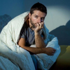 Hombre sentado en el sofá por la noche con miedo.-123RF