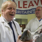 Un exultante Boris Johnson (izquierda) sostiene un salmón salvaje junto a Greg Essex, en el mercado de pescado de Billingsgate, en Londres, este miércoles.-AP / STEFAN ROUSSEAU