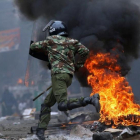 Un agente antidisturbios salta una barricada en llamas levantada por seguidores del opositor Raila Odinga, en Mathare (Nairobi), el 12 de agosto.-REUTERS / THOMAS MUKOYA