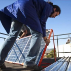 Un hombre instala placas fotovoltaicas en la cubierta de un edificio.-ARCHIVO / JOAN PUIG