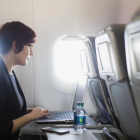 Una usuaria navega por internet a través de wifi en un avión con su portátil.-