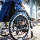 Una mujer en silla de ruedas frente a una parada de autobús.